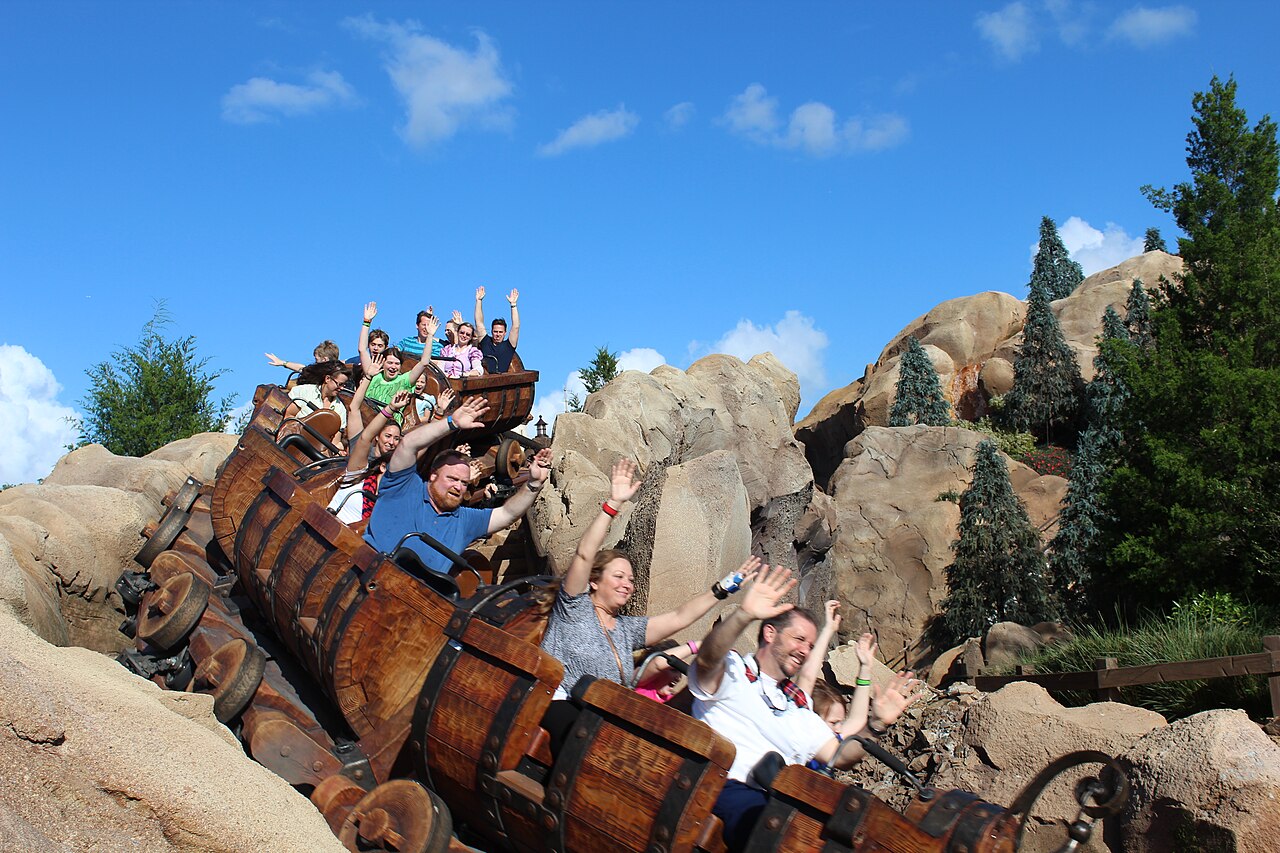 Riders with their arms up in wooden mine cars on Seven Dwarfs Mine Train