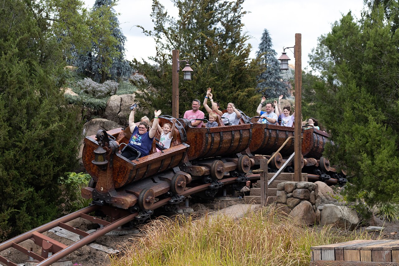 A full train of barrel cars sitting on the track, riders waving