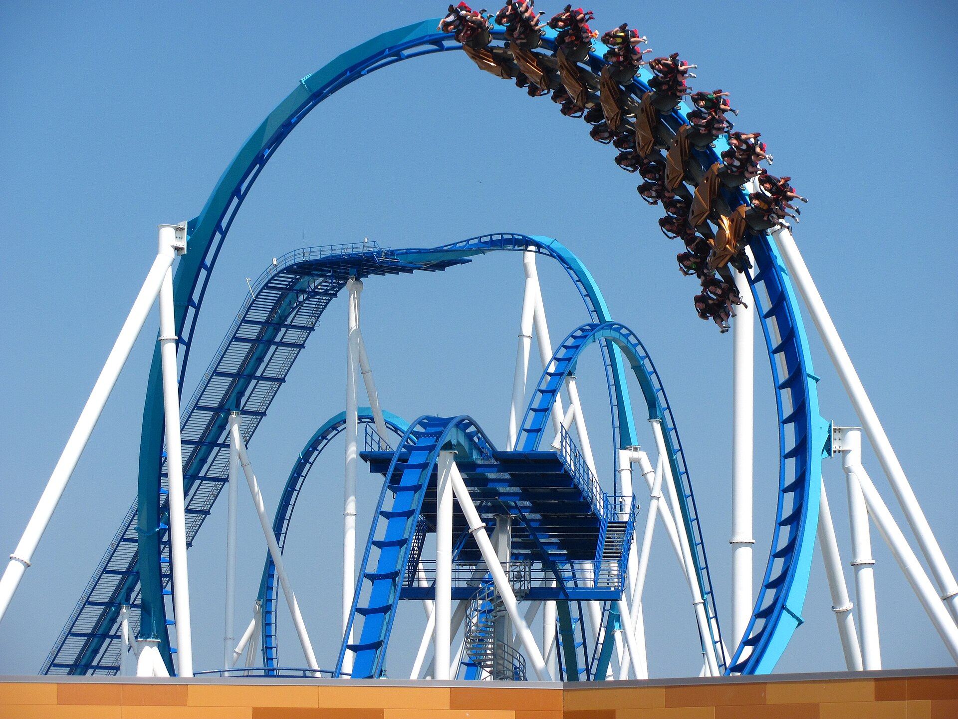 A full GateKeeper train rolling upside down over the blue track, blue sky behind