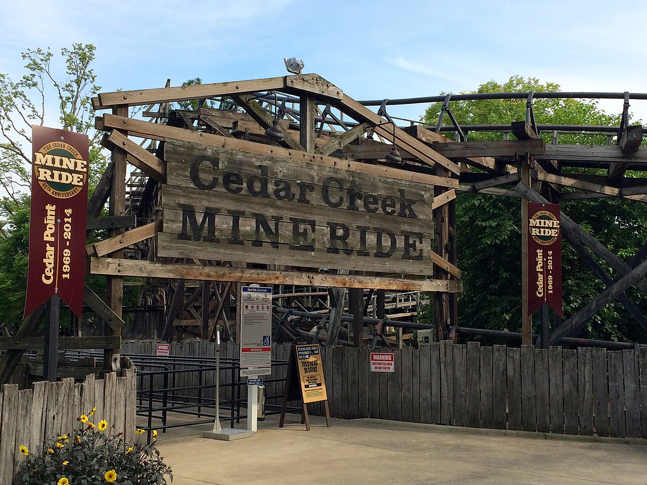 Cedar Point's Cedar Creek Mine Ride entrance sign with banners nearby commemorating the ride's 45th anniversary