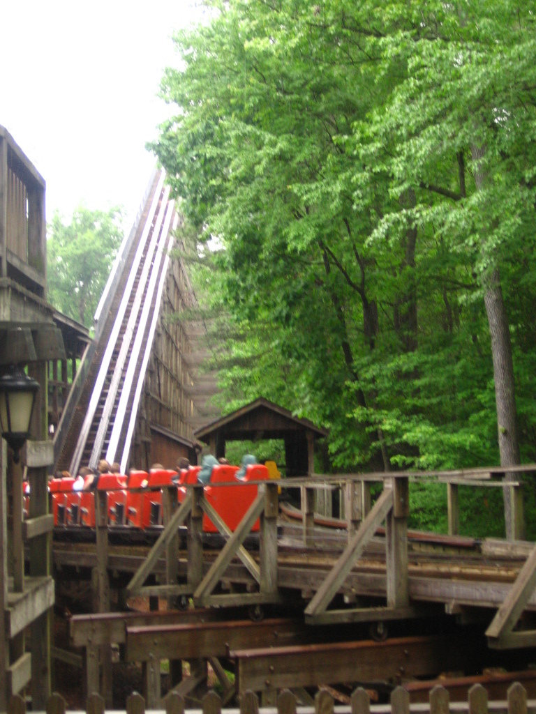 A train of the Kings Dominion park's Grizzly wooden roller coaster passing over a track switch and climbing the lift hill